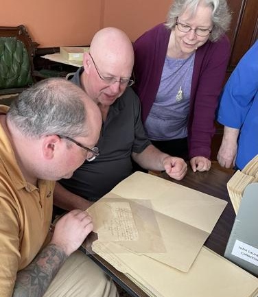 Current and former directors of the Fort Ontario Historic Site, Matthew McVittie, left, and Paul Lear, right, examine papers from the John Laurance collection at the Richardson-Bates House Museum with County Historian Deb Allen