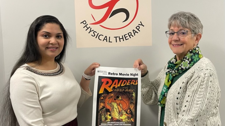Dr. Singh and Eva Corradino holding a Retro Movie Night Poster in Dr. Singh's office